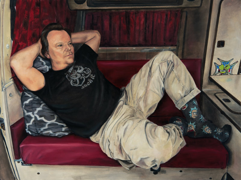 Brodalisque Couchée en Westfalia includes a dude leaning back on dark red cushions inside of a tan camper van. He poses with both hands behind his head and his knees bent. 